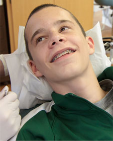 A smiling teenager with braces resting in a dental chai