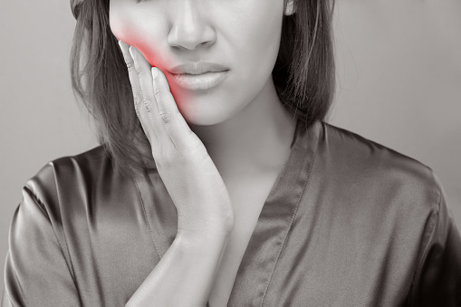 Woman suffering from inflammation of the jaw holding her cheek